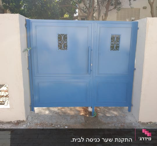 שער מתכת כחול עם עיטורים, מותקן על קיר בטון